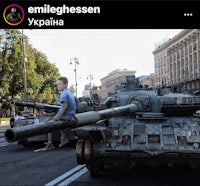 a boy is standing on top of a tank in a city