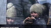 two children in hats look out of a window