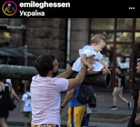 a man holding a baby on top of a pole